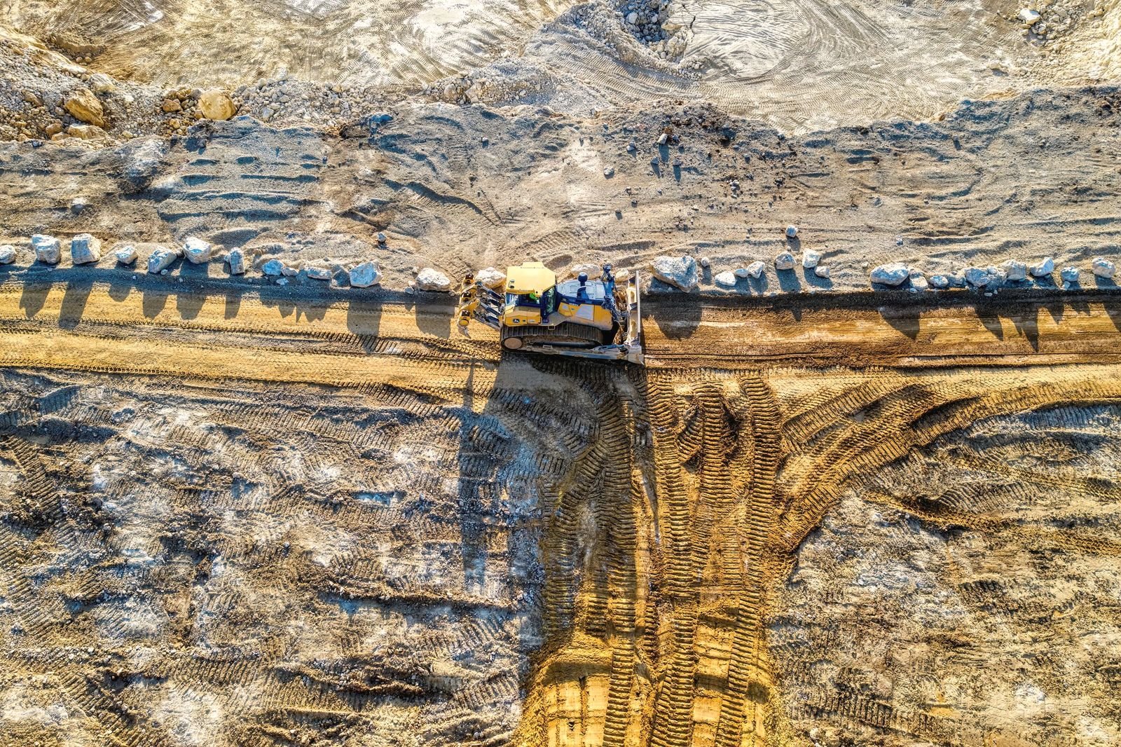 Bulldozer seen from above, pushing fill along a graded line
