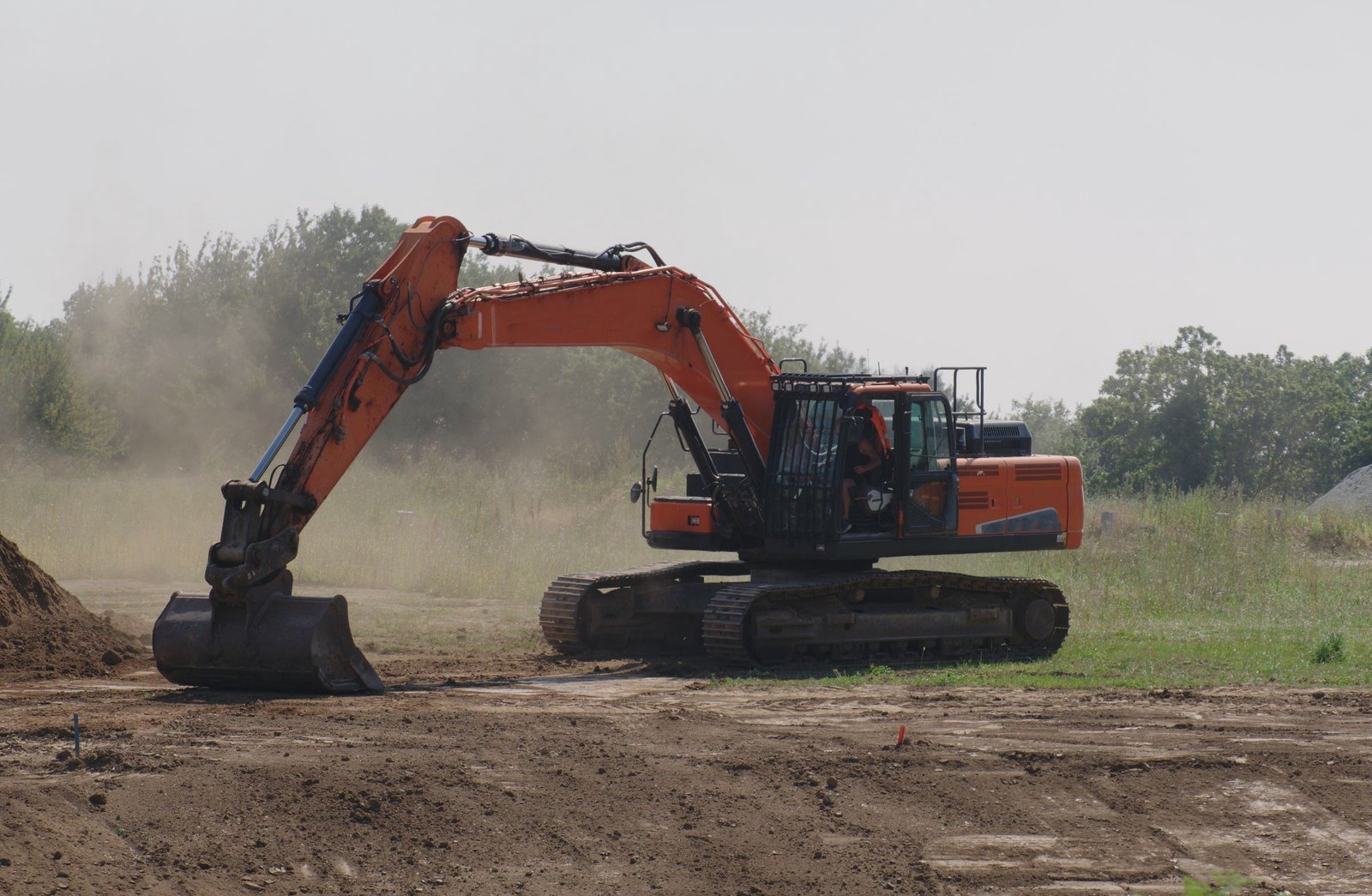 Excavator leveling dirt on a flat building site